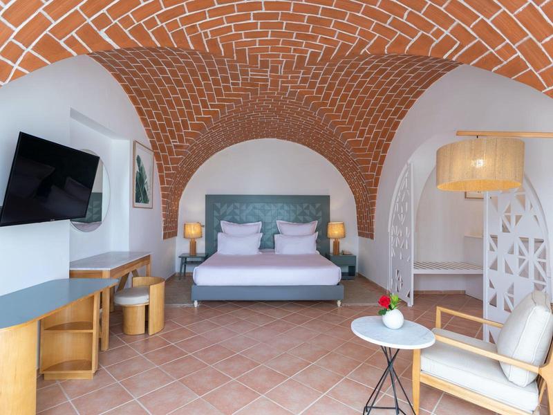 Camera d'hotel moderna con letto matrimoniale, muro in mattoni e decorazioni eleganti.