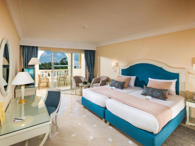 Camera d'hotel elegante con due letti singoli, balcone e vista mare.