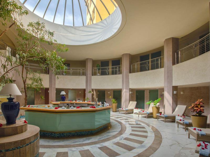 Interno circolare di un atrio d'hotel con piante e luce naturale da una cupola.