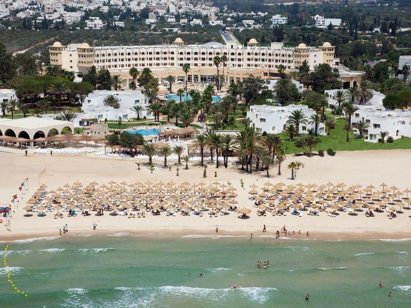 Hotel sul mare con spiaggia sabbiosa attrezzata con ombrelloni e lettini.