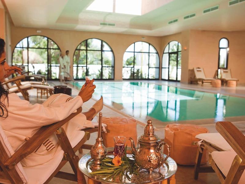 Due donne si rilassano accanto a una piscina interna con bevande.