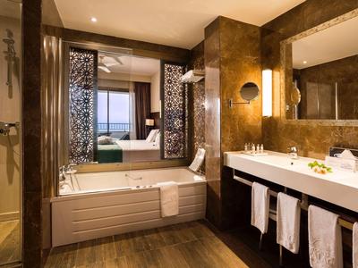 Modern hotel bathroom with bathtub, large vanity, and warm lighting.