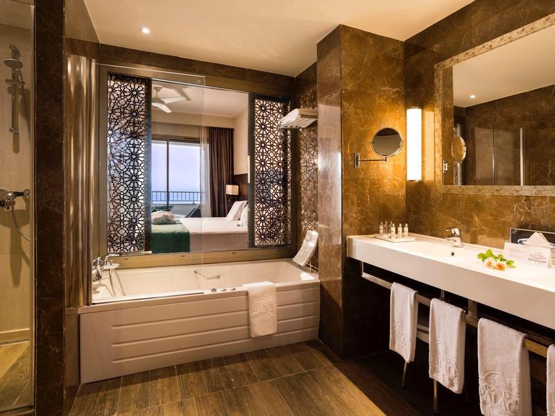 Modern hotel bathroom with bathtub, large vanity, and warm lighting.