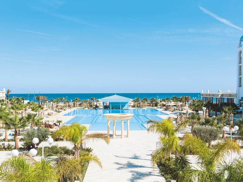 Large pool overlooking the sea with clear blue sky at a resort.