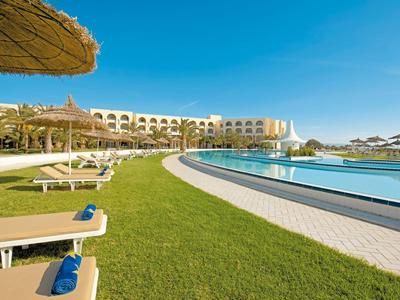 Gran piscina del hotel con sillas de descanso y sombrillas en clima soleado.