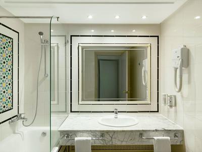 Moderner Hotelbadezimmer mit Spiegel, Waschbecken und Badewanne mit Glaswand.