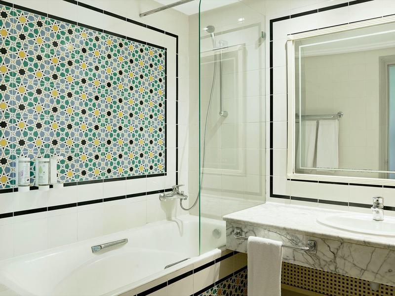 Moderne Badezimmer mit Badewanne, Waschbecken mit großem Spiegel und bunten Wandfliesen.