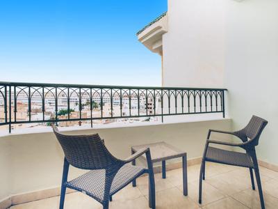 Balkon mit zwei Stühlen und Geländer mit Blick auf die Stadt bei klarem Himmel.