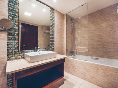 Modernes Badezimmer mit Waschbecken, großem Spiegel und Badewanne mit Duschabtrennung