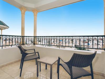 Balkon mit zwei Stühlen, kleinem Tisch und Blick auf Stadt unter klarem Himmel.