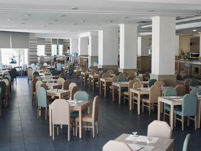 Spacious modern dining room with numerous tables and chairs in neutral tones.