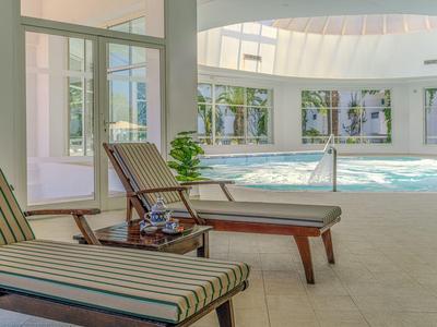 Indoor pool area with lounge chairs and large windows in a hotel.