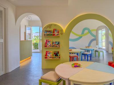 Bright, child-friendly interior with play tables, colorful chairs, and shelves filled with toys.