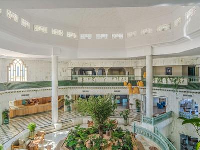 Large circular hotel lobby with plants and seating areas.