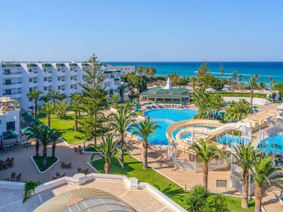 Hotel complex with multiple pools, green palm trees, and direct sea view.
