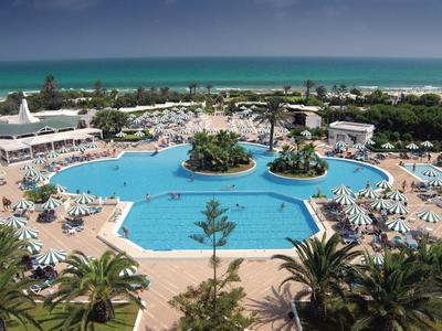 Groot buitenzwembad met parasols en ligstoelen dicht bij het strand.
