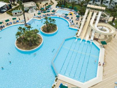 Wasserpark mit Schwimmbecken, Rutschen, Inseln mit Palmen und vielen Badegästen.