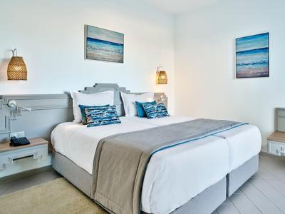 Modern hotel room with two single beds, gray furniture, and maritime wall art.