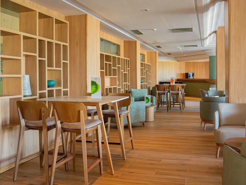 Interior of a modern lounge with wooden furniture, bar stools, and comfortable armchairs.