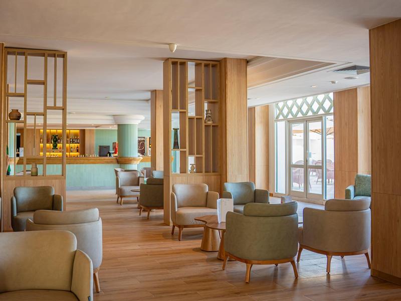 Bright hotel lounge area with comfortable armchairs and wood paneling.