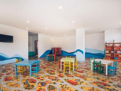 Colorful children's playroom with small tables, chairs, and play equipment.