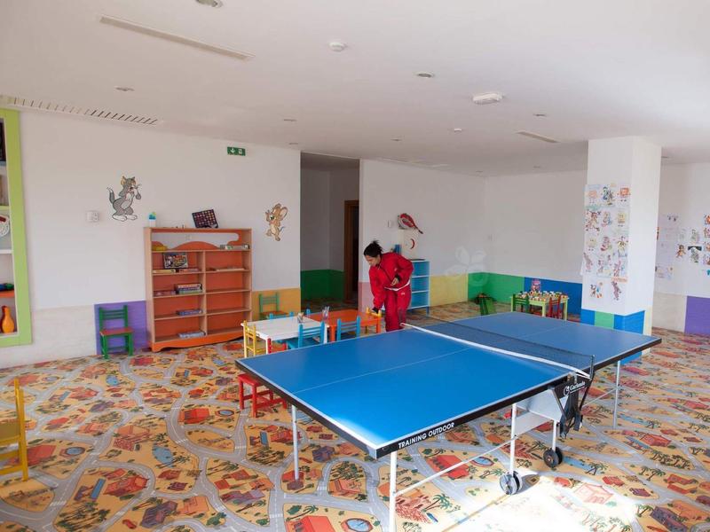 Children's playroom with ping pong table and colorful carpet in bright room.