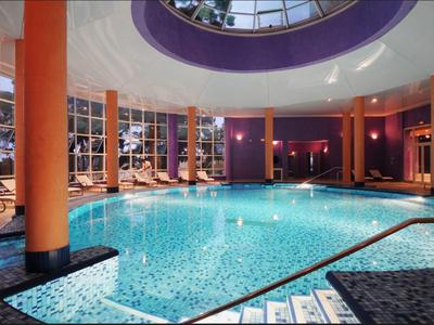 Innenpool mit orangefarbenen Säulen und Liegestühlen in einem modernen Hotel.