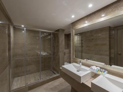 Modernes Badezimmer mit begehbarer Dusche, zwei Waschbecken und großem Spiegel.