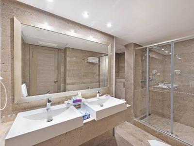 Modernes Badezimmer mit zwei weißen Waschbecken, großem Spiegel und Dusche mit Glasscheiben.