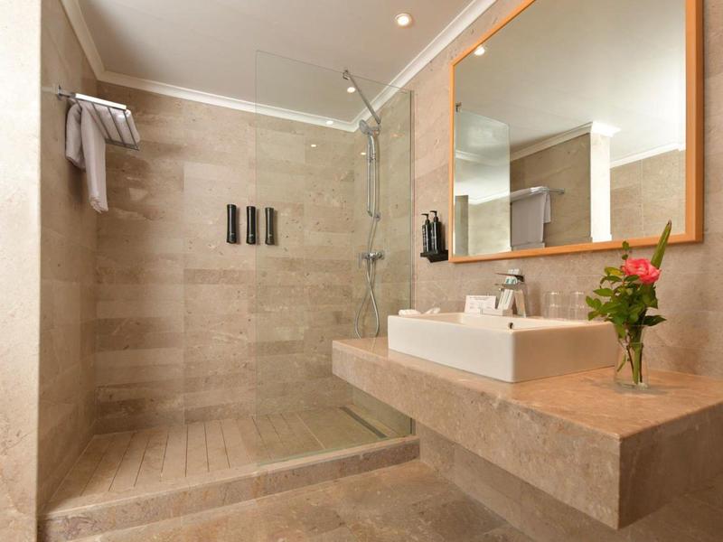 Modernes Badezimmer mit ebenerdiger Dusche, Waschbecken auf großem Waschbecken und Spiegel.