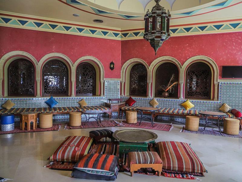 Cozy oriental seating area with colorful cushions and low tables in a richly detailed room.