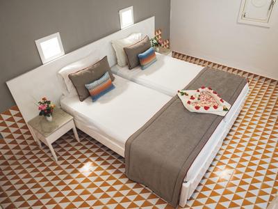 Chambre d'hôtel moderne avec grand lit, murs clairs et sol géométrique frappant.