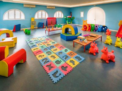 Salle de jeux colorée pour enfants avec tapis souples, sièges et jouets.