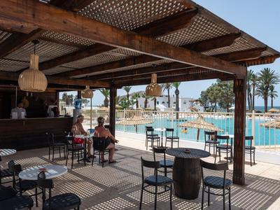 Überdachte Poolbar mit Sitzgelegenheiten und Blick auf den Pool und Palmen