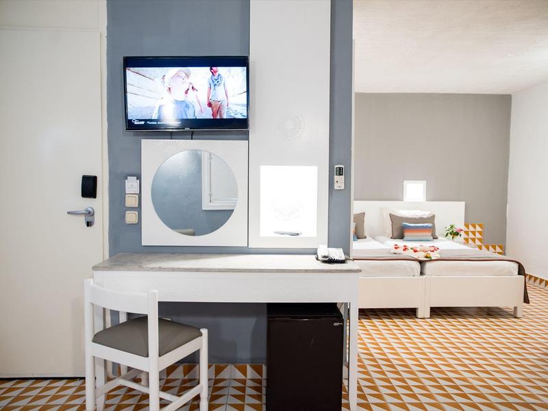 Chambre d'hôtel moderne avec bureau, chaise, lit et télévision murale.