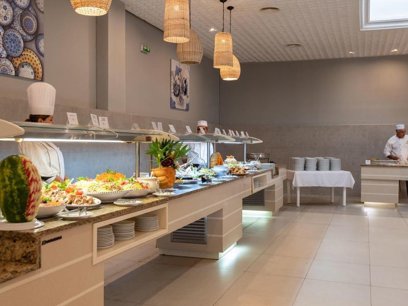 Salle de petit-déjeuner lumineuse avec buffet et diverses nourritures.