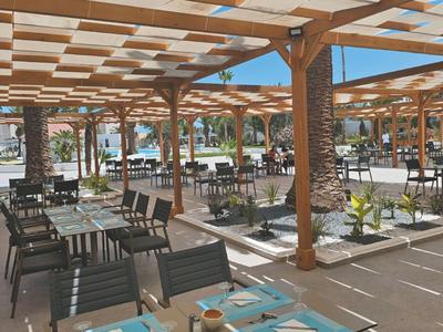 Open dining area with wooden lattice roof and modern outdoor furniture in daylight.