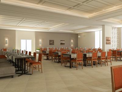 Gran comedor de hotel con mesas y sillas naranjas y grises, luz natural e iluminación cálida