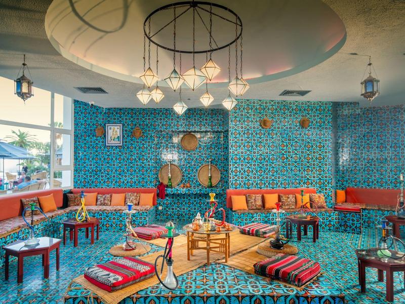 Salón acogedor decorado con colores vivos, cojines, mesas y diseño oriental.