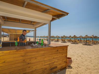 Dřevěný plážový bar s barmanem a lehátky s slunečníky na písku