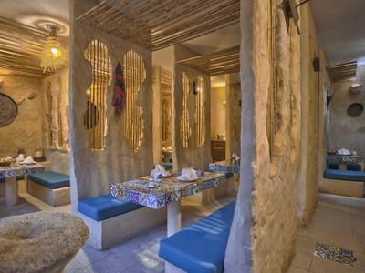 Rustikální restaurace s dřevěnými stěnami a modrými lavicemi, stoly prostřené nádobím.