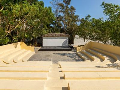 Amfiteátr s stupňovitými sedadly z světlého kamene pod stromy.