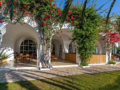 Wit gebouw met bogen, bloeiende klimplanten en een terras met stoelen