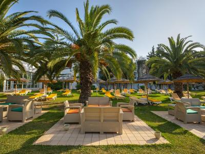 Zonterras met gezellige zitgedeeltes en palmboom in de hoteltuin bij heldere lucht.