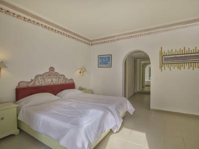 Jasně zařízená ložnice s manželskou postelí, nočními stolky a přístupem na chodbu.