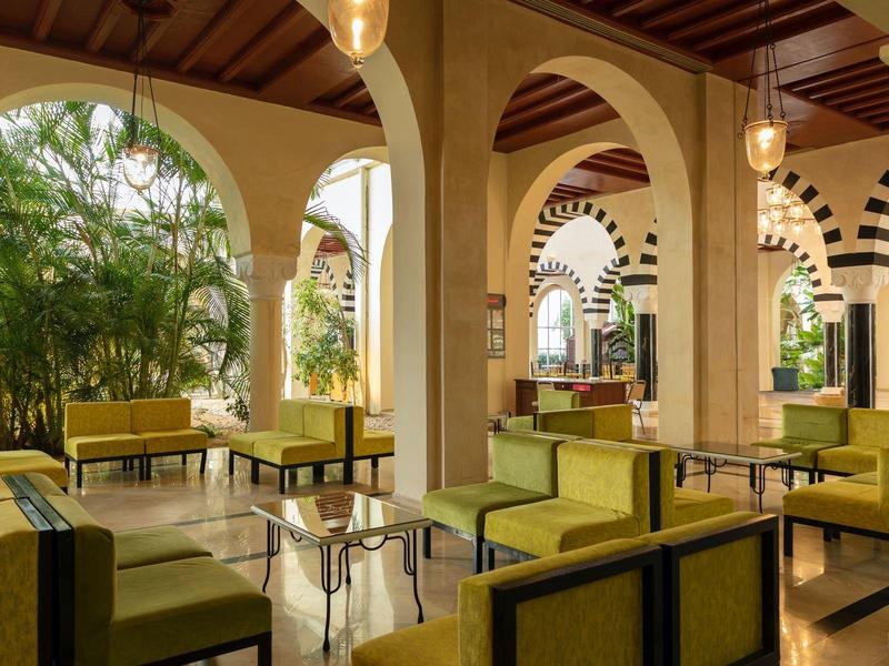 Pohodlná posezení s žlutými pohovkami a velkými oblouky na otevřené hotelové terase.