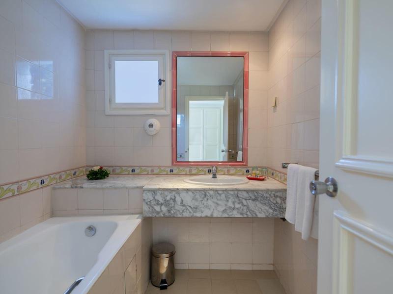 Světla koupelna s vanou, mramorovým umyvadlem a zrcadlem na stěně