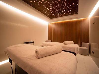 Moderne wellnessruimte met twee massagetafels en zachte verlichting.