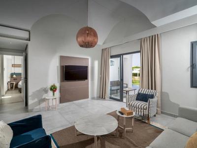 Helles Wohnzimmer mit weißem Sofa, blauem Sessel, Marmor-Tisch und Zugang zur Terrasse.