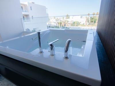 Moderner weißer Whirlpool auf Balkon mit städtischem Hintergrund und blauem Himmel.